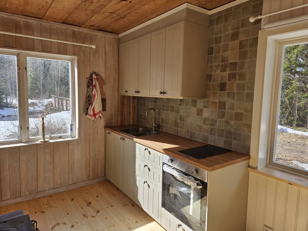 Renoverat stugkök med nya skåp, kakel och trägolv