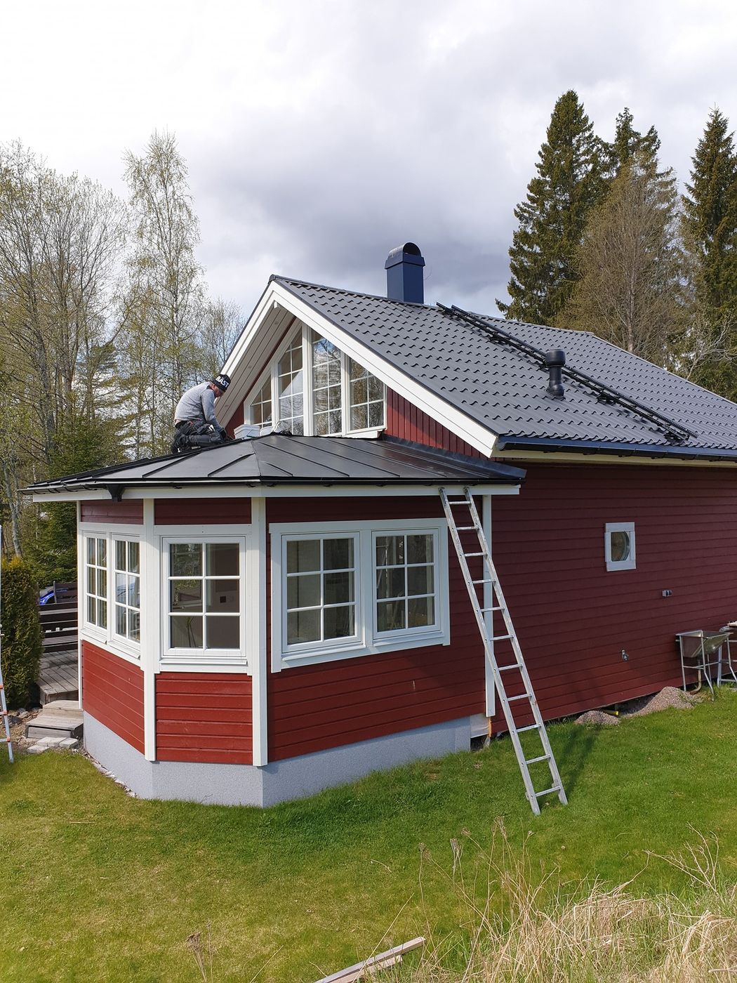 Rött hus med nytt svart plåttak och burspråk